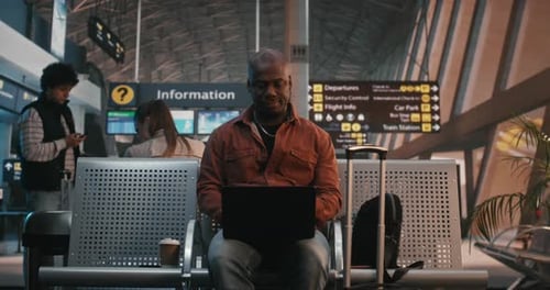 Focused Freelancer Working on Laptop at Airport Gate During Flight Delay