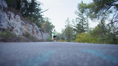Man in sportswear jogging on a flat outdoor road, running directly at the camera