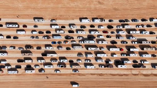 Lots of cars, vans and campervans riding by the desert in rows.