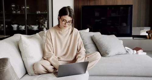 Woman Working on Laptop on Sofa at Home