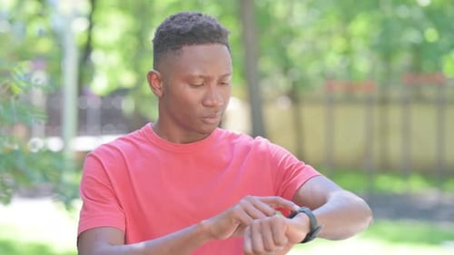 Casual African Man Using Smartwatch Outdoor in Park