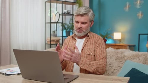 Man Video Conferencing on Laptop at Home