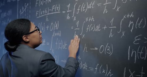 Woman Writes Formulas on Chalkboard in Classroom