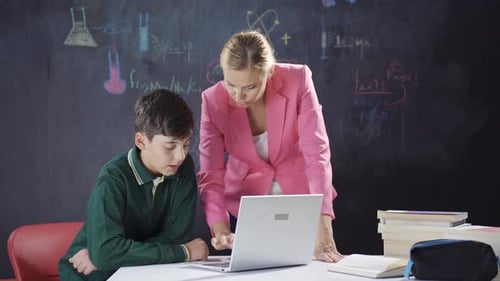 The teacher is teaching her student how to use a laptop.
