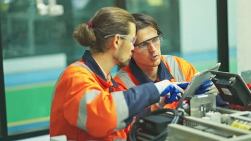 Side view two engineer or technician worker men with one hold tablet and discuss about machine
