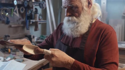 Man Carefully Sands Wooden Spoon with Sandpaper