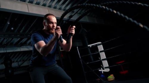 junger männlicher Bodybuilder macht Übungen mit einem Seil in den Händen im Fitnessstudio und bereitet sich auf das Bodybuilding vor