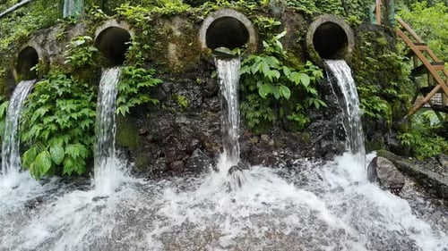 Clear Water Flows from Concrete Pipes into Pool