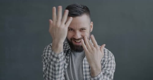 Young Adult With Beard Smiles and Hand Gestures