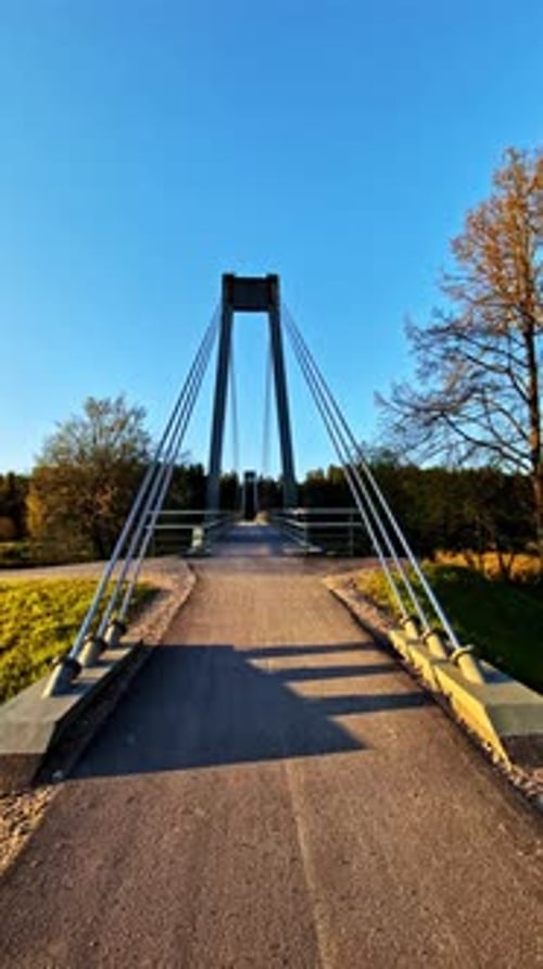 Suspension pedestrian bridge in Valmiera, Latvia at golden hour, vertical