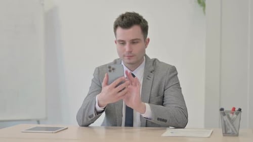 Young Businessman Browsing Internet on Smartphone in Office