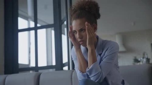 Stressed Woman Massaging Temples on Sofa