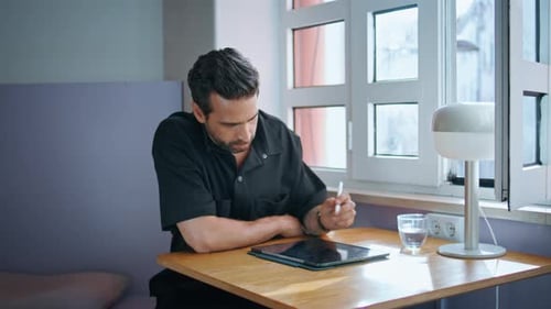 Cafe Manager Writing Tablet at Small Table Closeup Man Working on Pad Computer