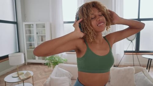 Energetic Young Woman Dancing with Headphones in Apartment