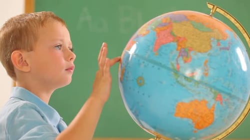 Boy Touches Globe in Classroom Setting