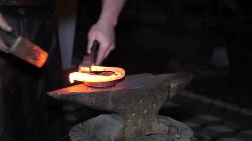 Blacksmith Forging Red-Hot Horseshoe with Hammer and Anvil