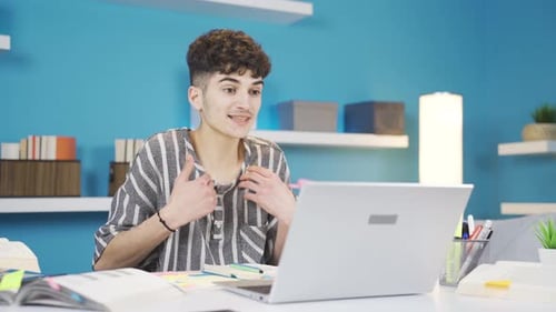 Young Adult Studying Online Using Laptop at Desk