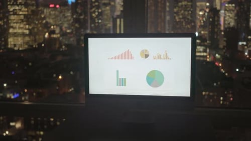 Computer Monitor Displaying Charts at Night in City