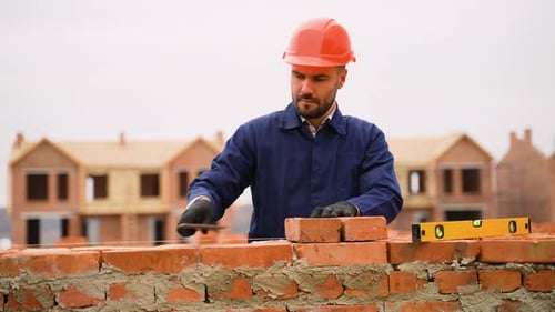 Albañil trabaja en la pared de una obra de construcción de una casa adosada