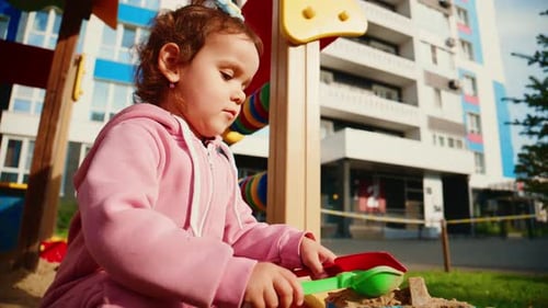 Jeune enfant jouant dans un bac à sable s'engageant dans un jeu créatif avec des jouets colorés dans un terrain de jeu dynamique
