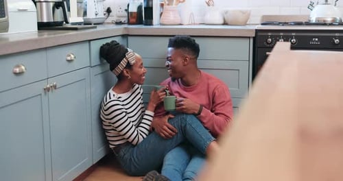 Smiling Couple Enjoying Coffee Together on Kitchen Floor