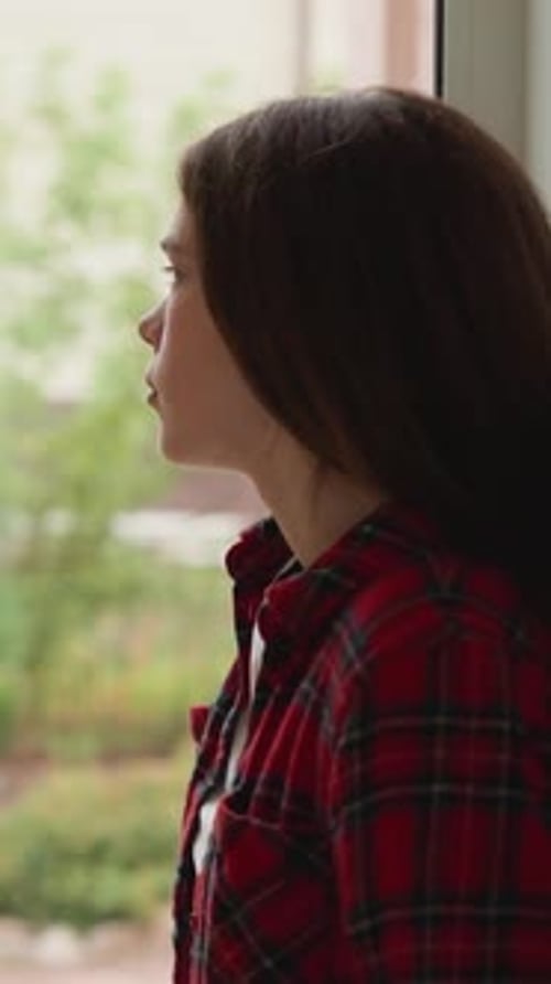 Woman Staring Out Window On Overcast Day