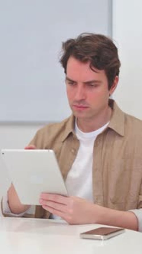 Man Using Tablet Computer Sitting at Desk Indoors