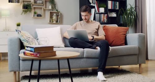 Man Uses Laptop on Couch in Living Room