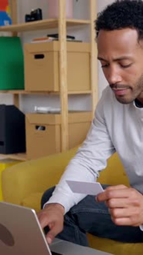 Young Adult Using Laptop and Holding Card