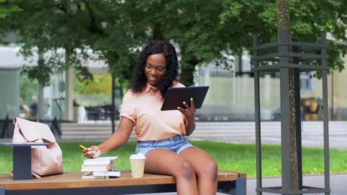 Smiling woman studies on tablet outdoors