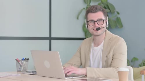 Smiling Young Businessman with Headset in Call Center