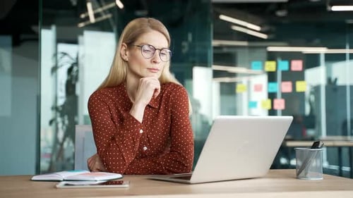 Woman Working Thoughtfully on Laptop in Modern Office