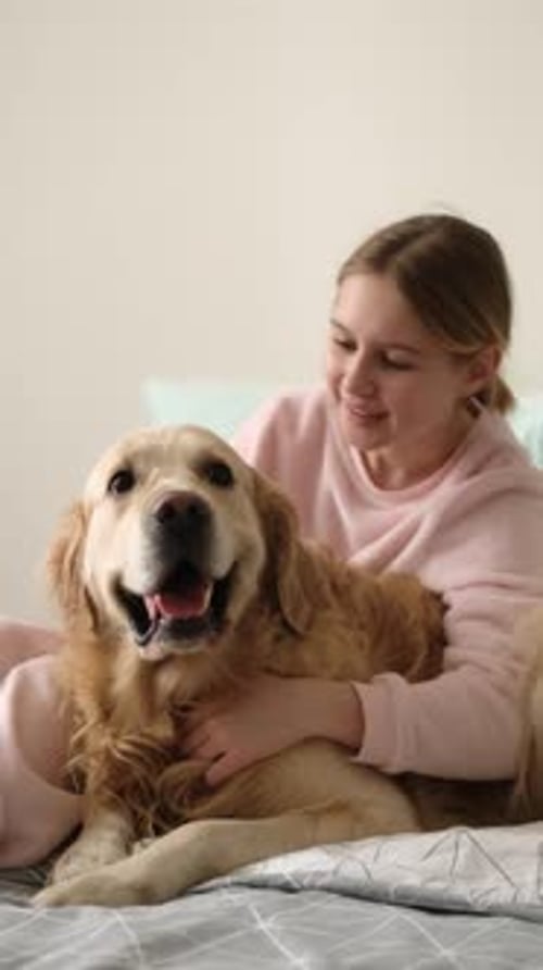 Teen Girl Cuddling Golden Retriever Dog in Bedroom