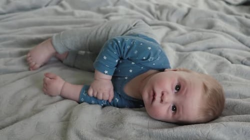 Cute baby lying on blanket looks at camera