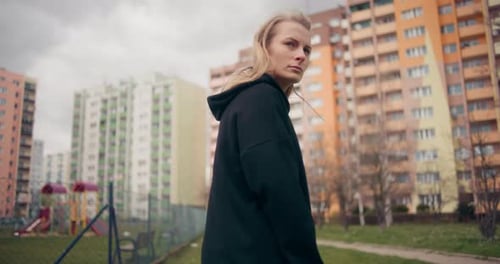 Woman with Headphones Standing Near Apartment Buildings