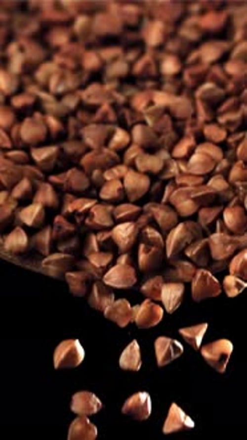 Buckwheat Falls From a Wooden Scoop on a Black Background Filmed on a Highspeed Camera at 1000 Fps