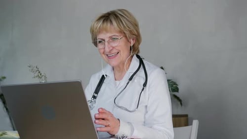 Mature Woman Doctor on Video Call with Laptop