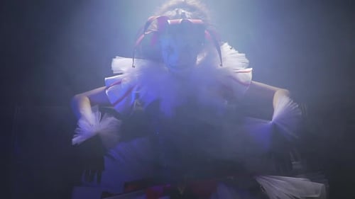 Eerie Clown in Jester Costume Sitting in Studio
