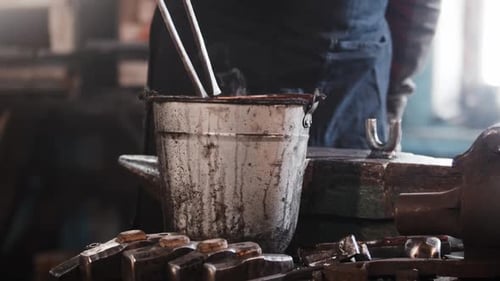 Blacksmith Cooling Hot Metal in Water Bucket