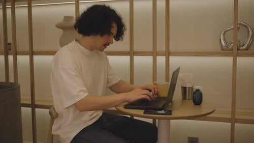 Side View of Man Who Sits in Cafe in Daytime and Using the Laptop for the Remote Work Freelancer