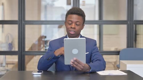 African Woman Doing Video Chat on Tablet in Office