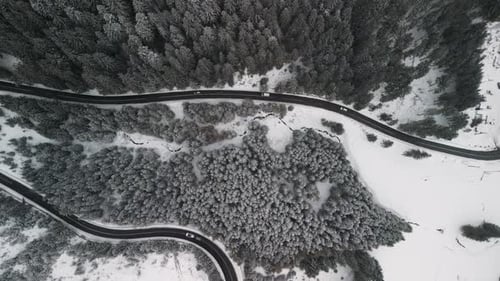 La vista aérea de un bosque cubierto de nieve y una carretera sinuosa invita a explorar la belleza de la naturaleza