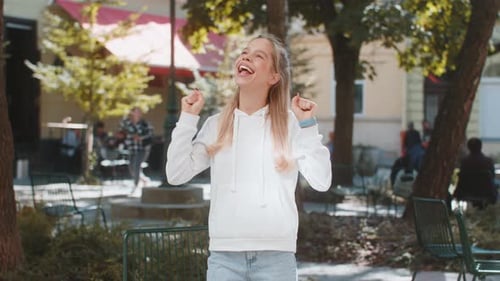 Young Woman Looking Surprised Clenching Fists Shocked By Sudden Victory Standing on City Street