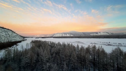 Majestic sunset over frozen river and snow-covered forest in Siberia during winter months