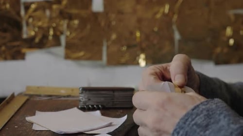 Ein älterer Künstler im Rollstuhl trägt Gold auf das Ölgemälde auf