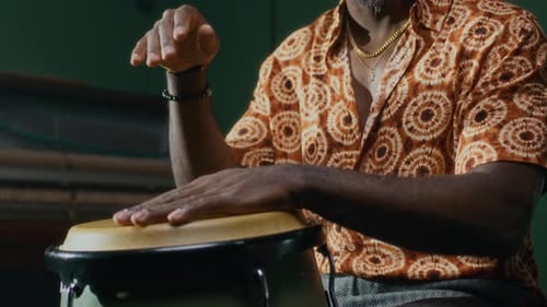 Hombre negro concentrado creando una composición rítmica mientras toca un tambor de conga