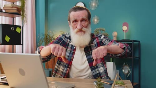 Senior Man Working on Laptop Computer at Home Office Showing Thumbs Down Sign Dislike Disapproval