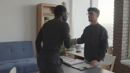 Two Businessmen Shaking Hands in Bright Office