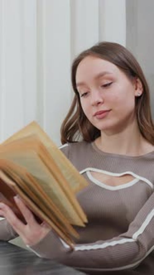 Livre de lecture pour jeune femme assise avec un sourire chaleureux dans un cadre confortable