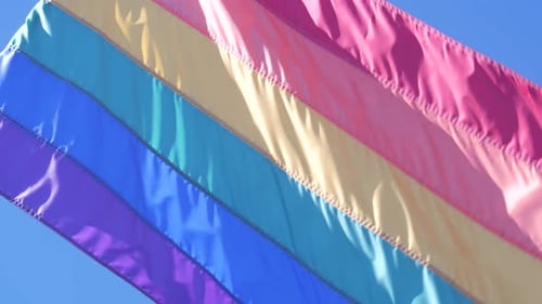 Rainbow Pride Flag Waving Against Blue Sky